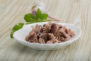 Boiled octopus in a bowl on wooden background photo