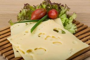 Maasdam cheese on wooden board and wooden background photo