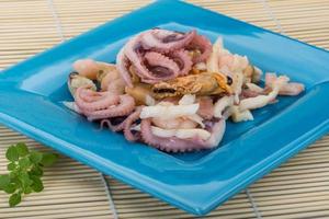 Seafood cocktail on the plate and wooden background photo