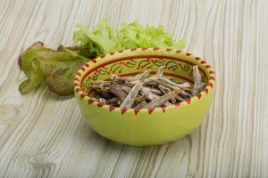 Dries anchovy in a bowl on wooden background photo