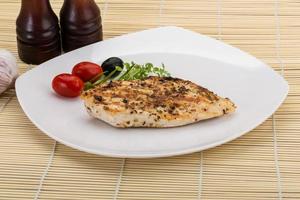 Grilled chichen breast on the plate and wooden background photo