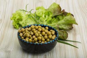 Marinated peas in a bowl on wooden background photo