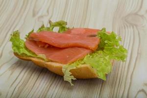 Salmon sandwich on wooden background photo