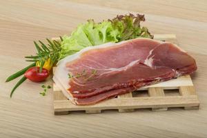 Prosciutto on wooden board and wooden background photo