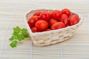 Cherry tomato in a basket on wooden background photo