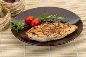 Grilled chichen breast on the plate and wooden background photo