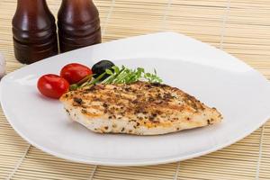 Grilled chichen breast on the plate and wooden background photo