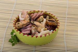 Seafood cocktail in a bowl on wooden background photo