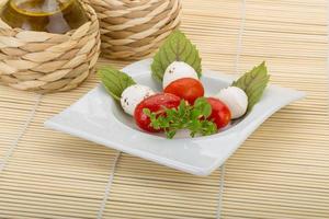 ensalada caprese en el plato y fondo de madera foto