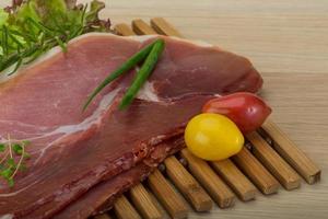 Prosciutto on wooden board and wooden background photo