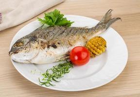 Grilled dorado on the plate and wooden background photo