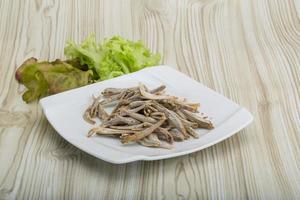 seca la anchoa en el plato y el fondo de madera foto