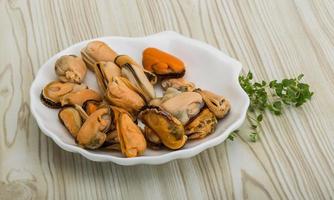 Mussels in a bowl on wooden background photo