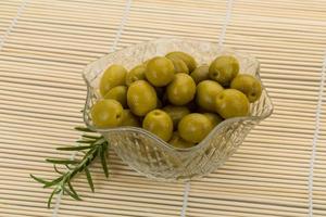 Green olives in a bowl on wooden background photo