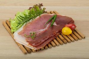 Prosciutto on wooden board and wooden background photo