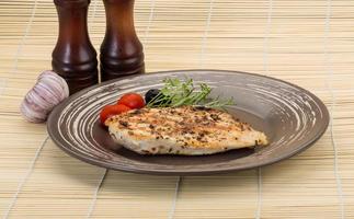 Grilled chichen breast on the plate and wooden background photo