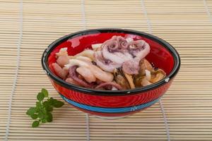 Seafood cocktail in a bowl on wooden background photo