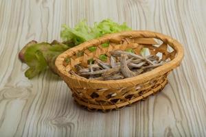 Dries anchovy in a basket on wooden background photo