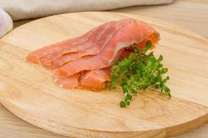 Sliced salmon on wooden board and wooden background photo