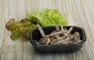Dries anchovy in a bowl on wooden background photo