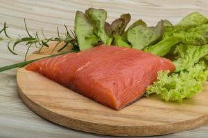 Salmon fillet on wooden board and wooden background photo