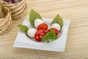 ensalada caprese en el plato y fondo de madera foto