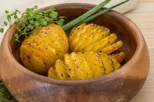 patata al horno en un bol sobre fondo de madera foto