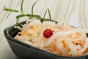 Sauerkraut in a bowl on wooden background photo