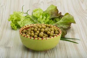 Marinated peas in a bowl on wooden background photo