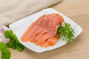 Sliced salmon on the plate and wooden background photo