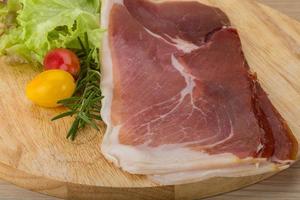 Prosciutto on wooden board and wooden background photo