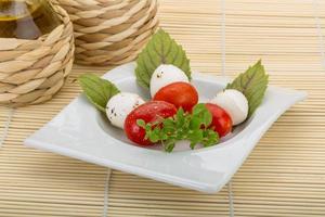 Caprese salad on the plate and wooden background photo