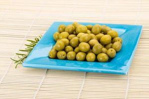 Green olives in a bowl on wooden background photo