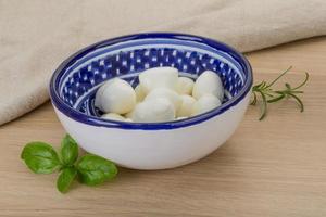 Mozzarella cheese in a bowl on wooden background photo