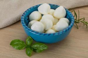 Mozzarella cheese in a bowl on wooden background photo