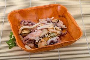 Seafood cocktail in a bowl on wooden background photo