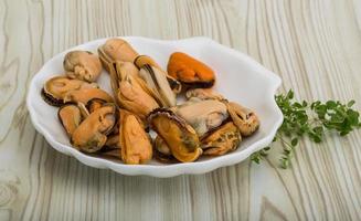 Mussels in a bowl on wooden background photo