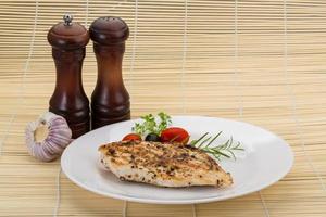 Grilled chichen breast on the plate and wooden background photo