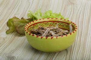 Dries anchovy in a bowl on wooden background photo