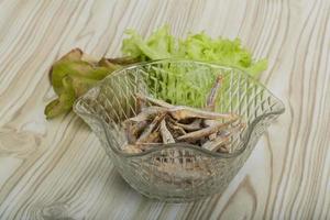 Dries anchovy in a bowl on wooden background photo