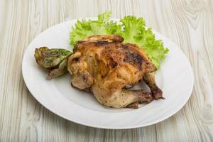 Roasted chicken on the plate and wooden background photo