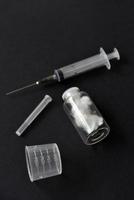 An empty medical syringe and a glass bottle on a black background. photo