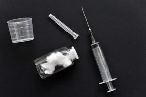 An empty medical syringe and a glass bottle on a black background. photo