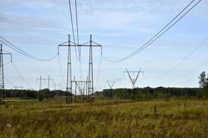 línea de alta tensión en el campo en un día de verano. una línea eléctrica en un campo verde. foto