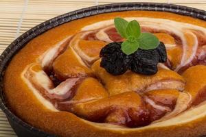 Plum cake in a bowl on wooden background photo