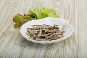 Dries anchovy in a bowl on wooden background photo