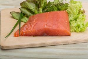 Salmon fillet on wooden board and wooden background photo