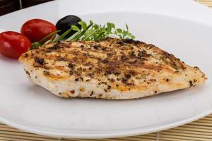 Grilled chichen breast on the plate and wooden background photo