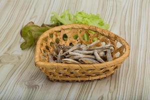 Dries anchovy in a basket on wooden background photo