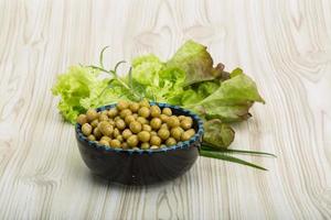 Marinated peas in a bowl on wooden background photo